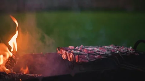 Meat is placed on a grill over an open flame, creating smoke and heat. The Stock Footage 345874738