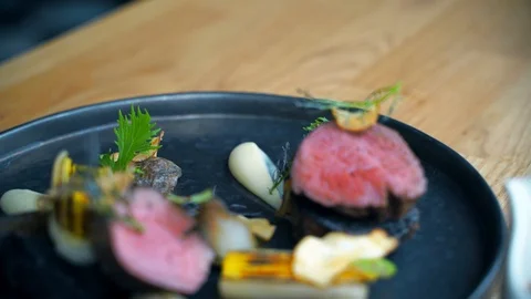 Meat poured with sauce served on a black plate 스톡 동영상 104052004