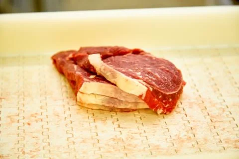 Meat processing plant. Slices of cut beef on the conveyor. Stock-Fotos