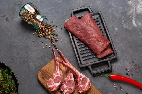 Meat Raw Fresh Mutton on the bone Spices Chesno and Rosemary on a black backg Stock Photos