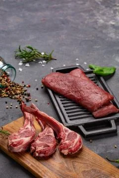 Meat Raw Fresh Mutton on the bone Spices Chesno and Rosemary on a black backg Stock Photos