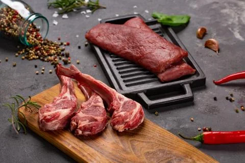 Meat Raw Fresh Mutton on the bone Spices Chesno and Rosemary on a black backg Stock Photos