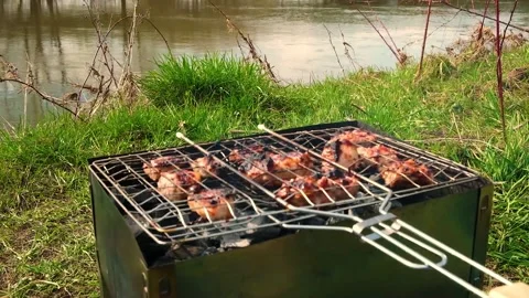 Meat is roasted on the grill on coals by the river Stock Footage 190570566