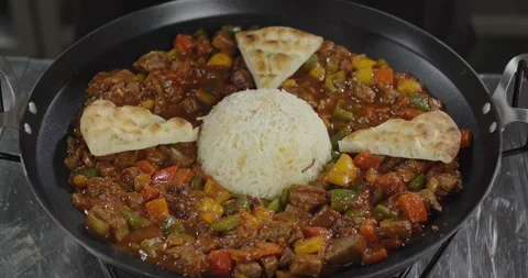 Meat roasted with vegetables. Chef puts Turkish flat bread on a dish in an iron Stock Footage 277658471