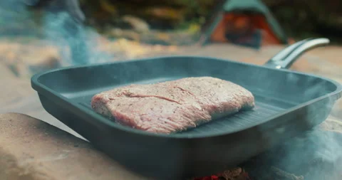 Meat roasting on fire, cooking steak on a pan in nature on a hike Stock Footage 264141962