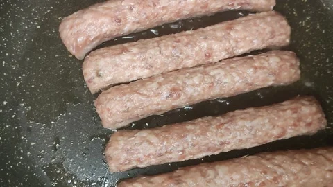 Meat sausages are quickly fried in a frying pan Stock Footage 199019436