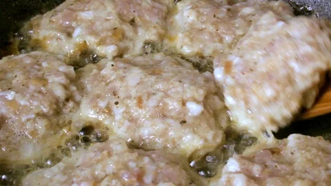 Meat schnitzels are turned over with a wooden spatula in a frying pan Video stock 90996556