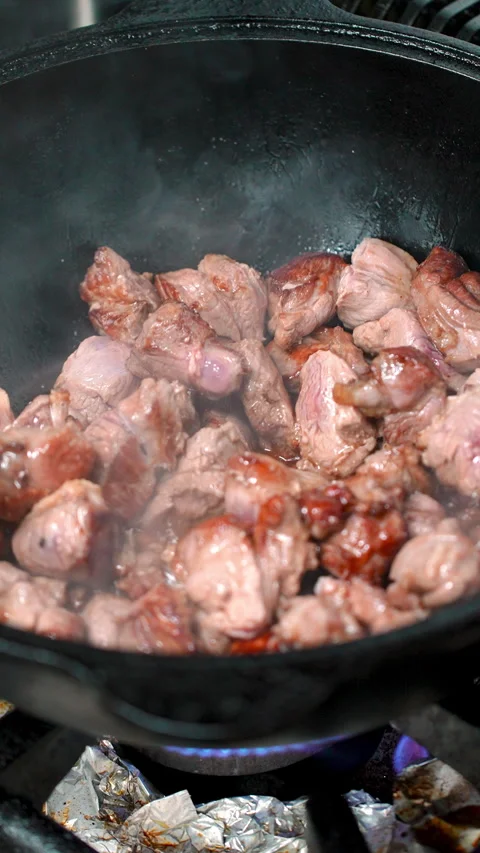 Meat sizzling, caramelizing inside heavy gauge wok, professional chef stirring Stock Footage 312022332