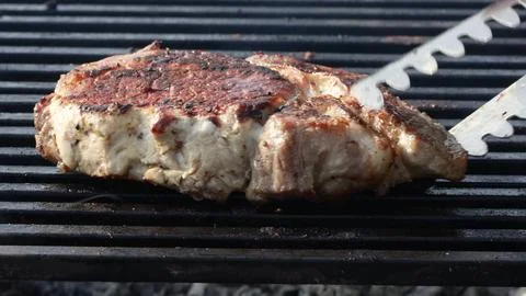 A meat steak fried on a wire rack with smoke and fire Stock-Fotos