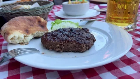 Meat steak on a plate with a piece of bread in a beach restaurant Stock Footage 251010748