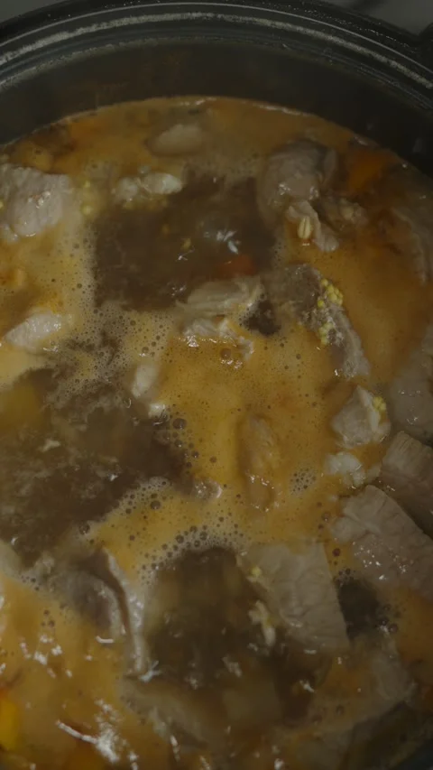 Meat stew with vegetables and grains simmering in multi-cooker Stock Footage 335391611