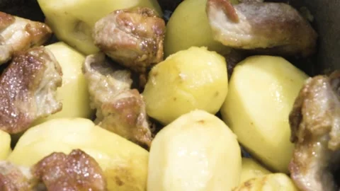 Meat is stewed with potatoes close-up. Fried meat with potatoes in the process Stock Footage 208935794