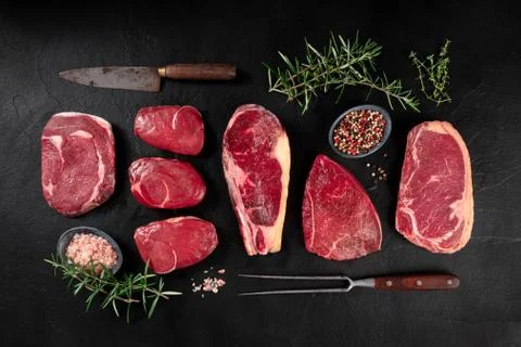 Meat, various cuts, overhead flat lay shot with a knife, a barbecue fork, salt Foto stock