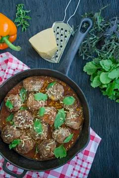 Meatballs in tomato sauce with greens. Dark wooden background. View from abov Stock Photos
