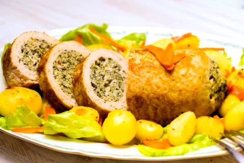 Meatloaf with spinach stuffing served with fried potatoes and carrot. Stock Photos