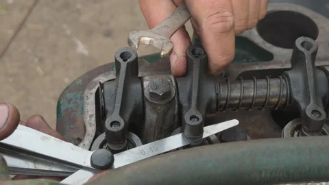 Mechanic adjusting engine valve clearance with feeler gauge and wrench Stock Footage 339037908