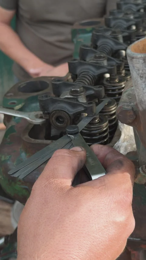 Mechanic adjusting engine valve clearance with feeler gauge Stock Footage 339038381