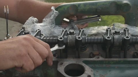Mechanic adjusting engine valves using wrench and feeler gauge Stock Footage 339037425
