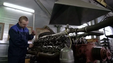 The mechanic adjusts the valve on the diesel engine. In hands tools Video stock 75050299