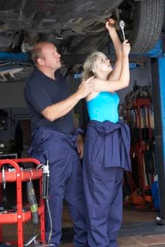 Mechanic and apprentice working on car Stock Photos