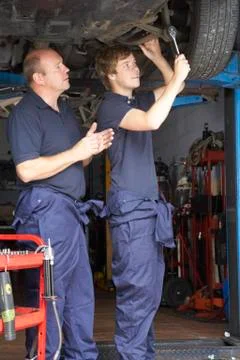Mechanic and apprentice working on car Stock Photos