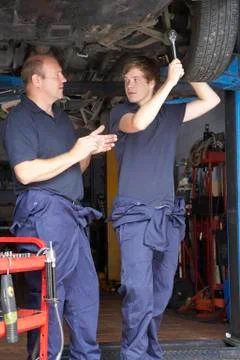 Mechanic and apprentice working on car Stock Photos