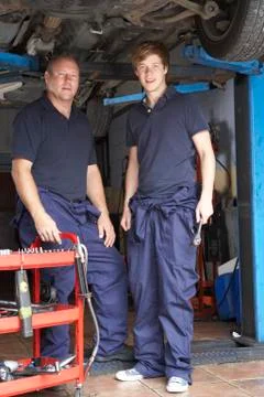 Mechanic and apprentice working on car Stock Photos