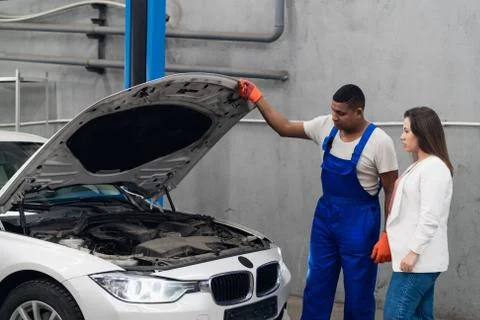 Mechanic and client inspect engine of car Stock Photos