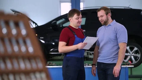 Mechanic and customer in the background of service and repair tools Stock Footage 70204022