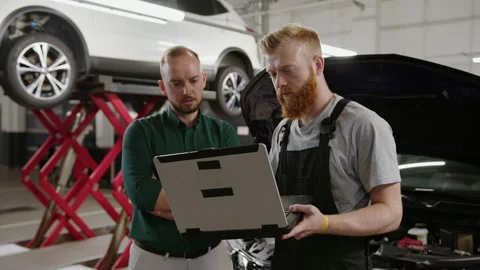 Mechanic and manager during car diagnostics on the background of a car service Stock Footage 240077772