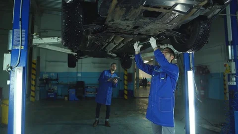 Mechanic And Trainee Working Under Car Stock Footage 70648074