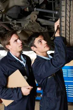 Mechanic And Trainee Working Under Car Stock Photos