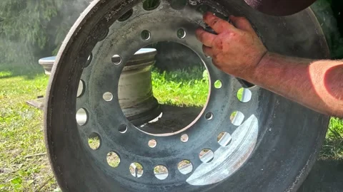 Mechanic applying spray paint or rust remover to a truck wheel rim for 스톡 동영상 346576621