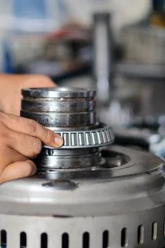 Mechanic assembling tapered roller bearing onto transmission gear shaft. Stock Photos