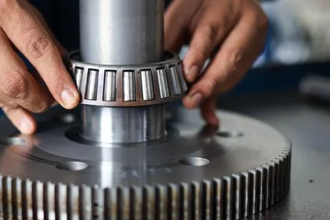 Mechanic assembling tapered roller bearing onto transmission gear shaft. Stock Photos