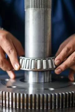Mechanic assembling tapered roller bearing onto transmission gear shaft. Stock Photos