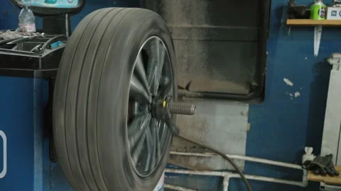 Mechanic balancing car wheel on machine in auto repair shop Stock Footage 337829623