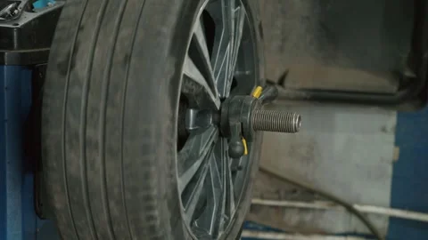 Mechanic balancing car wheel on machine in auto service garage Stock Footage 337829625