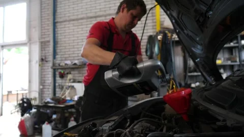 Mechanic in black gloves pours engine oil into a funnel, vehicle maintenance Video stock 316903863