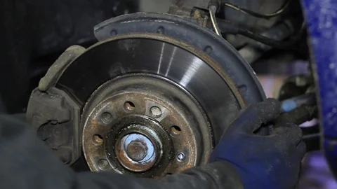 Mechanic for car checking brake system in a car at garage Stock Footage 103542988