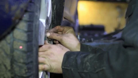 Mechanic for car checking brake system in a car at garage Stock Footage 103543692