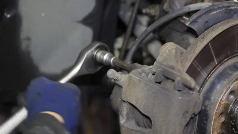 Mechanic for car checking brake system in a car at garage Stock Footage 103858226