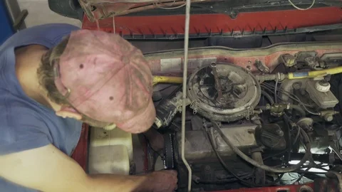 Mechanic changes timing belts and alternator at a service station Stock Footage 110864054