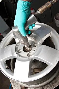 Mechanic changing car wheel in auto repair shop Stock Photos