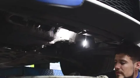 Mechanic changing the oil filter and inspecting the underside of a car Stock Footage 132304017