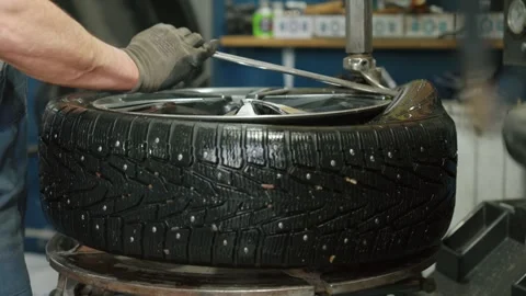 Mechanic changing studded winter tire on rim Stock Footage 337829593