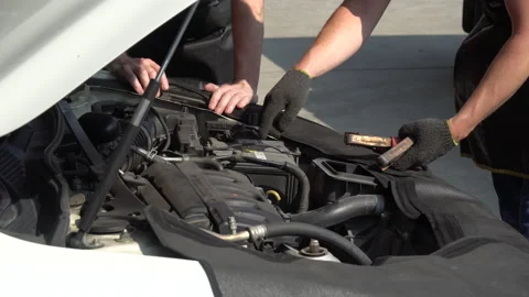 Mechanic checking and using battery jumper cables charg car in workshop at au Stock Footage 147367081