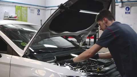 Mechanic checking a car engine and looking with a flashlight in a workshop 3 Stock Footage 132304034
