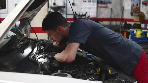 Mechanic checking a car engine and looking with a flashlight in a workshop 2 Stock Footage 132304035