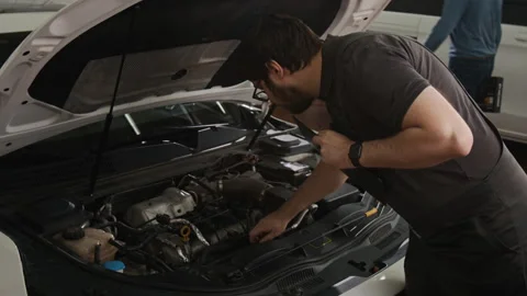 Mechanic Checking Car Engine and Filling out Cost Estimate Sheet for Repairs Vidéo 329433250